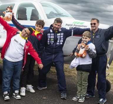 Pilotes et enfants prenant la pose pour l'opération rêves de gosses devant un avion